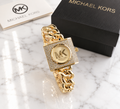 Michael Kors pavé crystal square lock watch with champagne gold dial on gold Cuban chain bracelet with MK logo and gift box