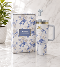 Stanley x LoveShackFancy Quencher tumbler in blue and white floral print with grey handle and bow straw topper, shown with matching floral gift box