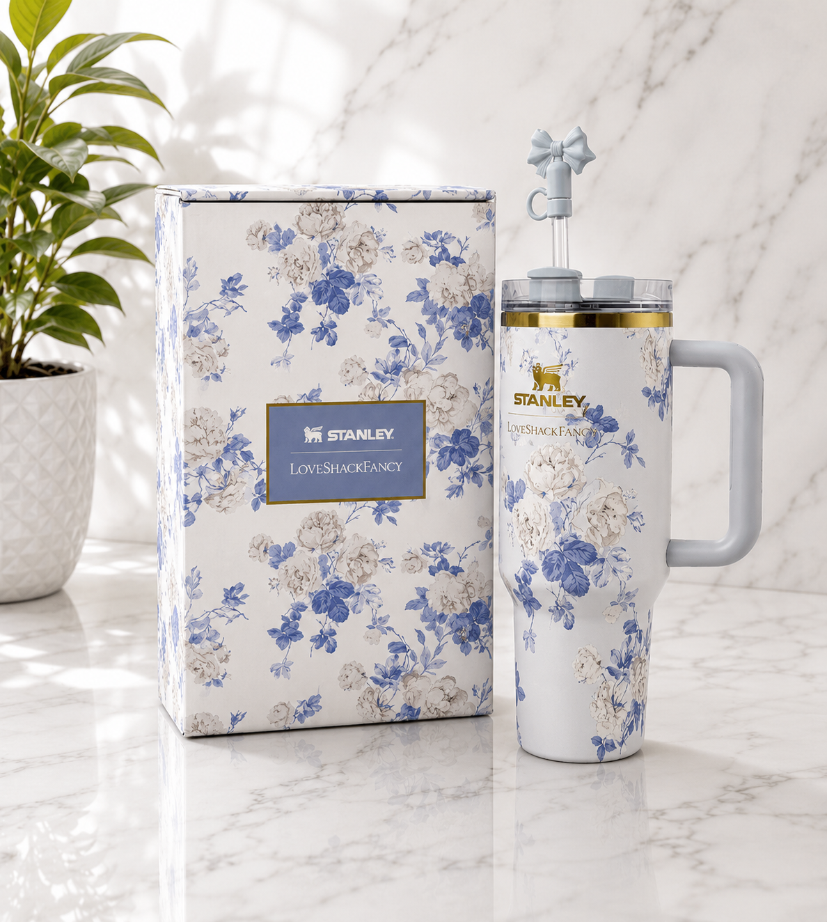 Stanley x LoveShackFancy Quencher tumbler in blue and white floral print with grey handle and bow straw topper, shown with matching floral gift box