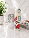 Starbucks insulated thermos bottle in cream white with colorful floral and hummingbird print, teal flip-top lid and ring, shown with Starbucks gift box