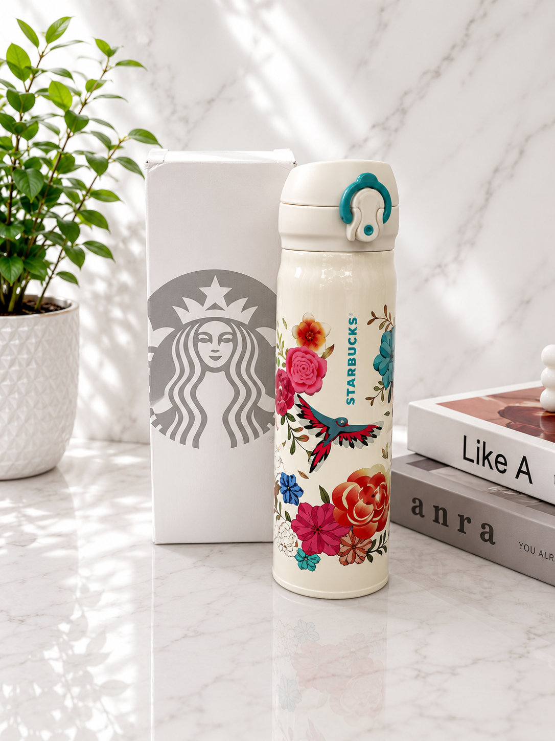 Starbucks insulated thermos bottle in cream white with colorful floral and hummingbird print, teal flip-top lid and ring, shown with Starbucks gift box