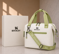 Stanley limited edition soft cooler lunch bag in cream white with sage green handles and crossbody strap, shown with white Stanley gift box