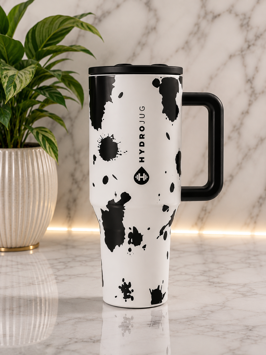 HydroJug Cow Print 40oz Tumbler with black handle and lid on marble surface