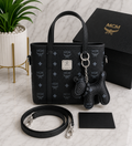 MCM Visetos Mini Tote Bag in black with silver hardware, bear charm and crossbody strap