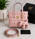 MCM Visetos Mini Tote Bag in blush pink with gold hardware, matching bear charm and crossbody strap