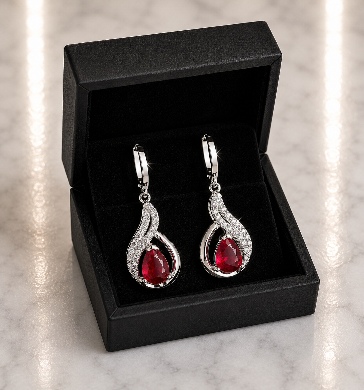 Ruby Red Teardrop and CZ Swirl Huggie Drop Earrings in silver displayed in a black luxury gift box