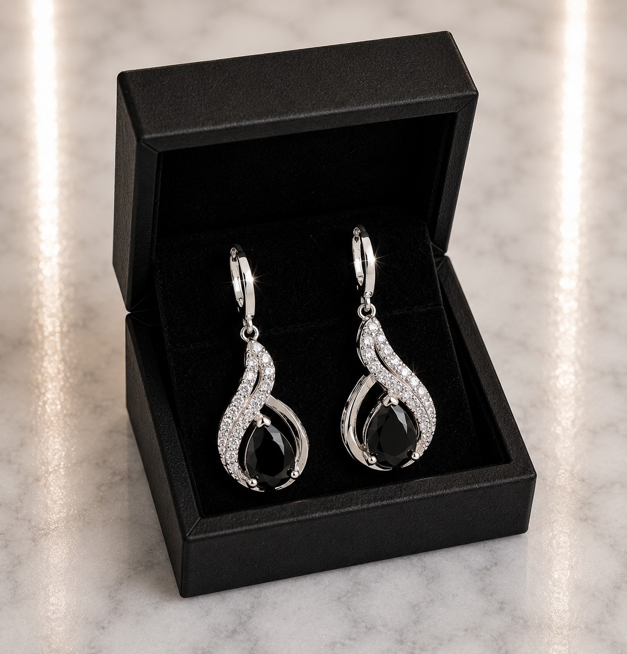 Black Onyx Teardrop and CZ Swirl Huggie Drop Earrings in silver displayed in a black luxury gift box