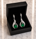 Emerald Green Teardrop and CZ Swirl Huggie Drop Earrings in silver displayed in a black luxury gift box